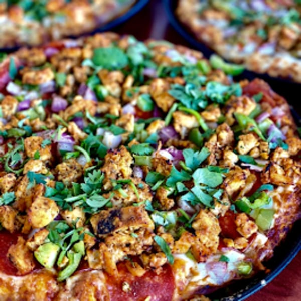 Close-up of a Parktown Pizza with chicken, red onions, green peppers, and cilantro.