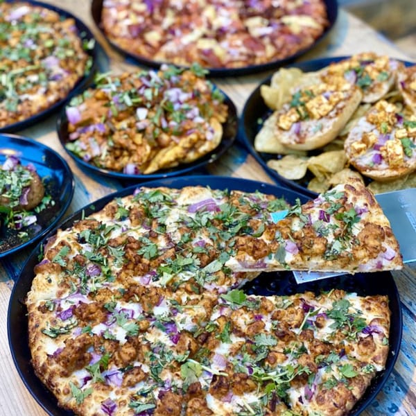 A table laden with various Parktown Pizza dishes, including pizzas, loaded potatoes, and bruschetta.